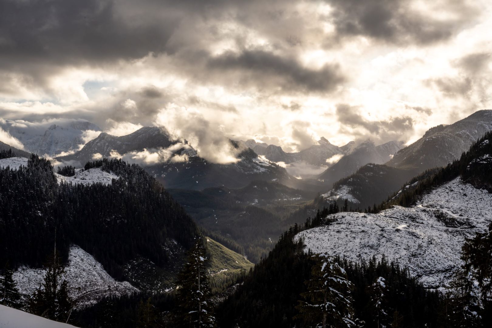 A snow-covered mountain range riddled with clear cuts on Northern Vancouver Island.